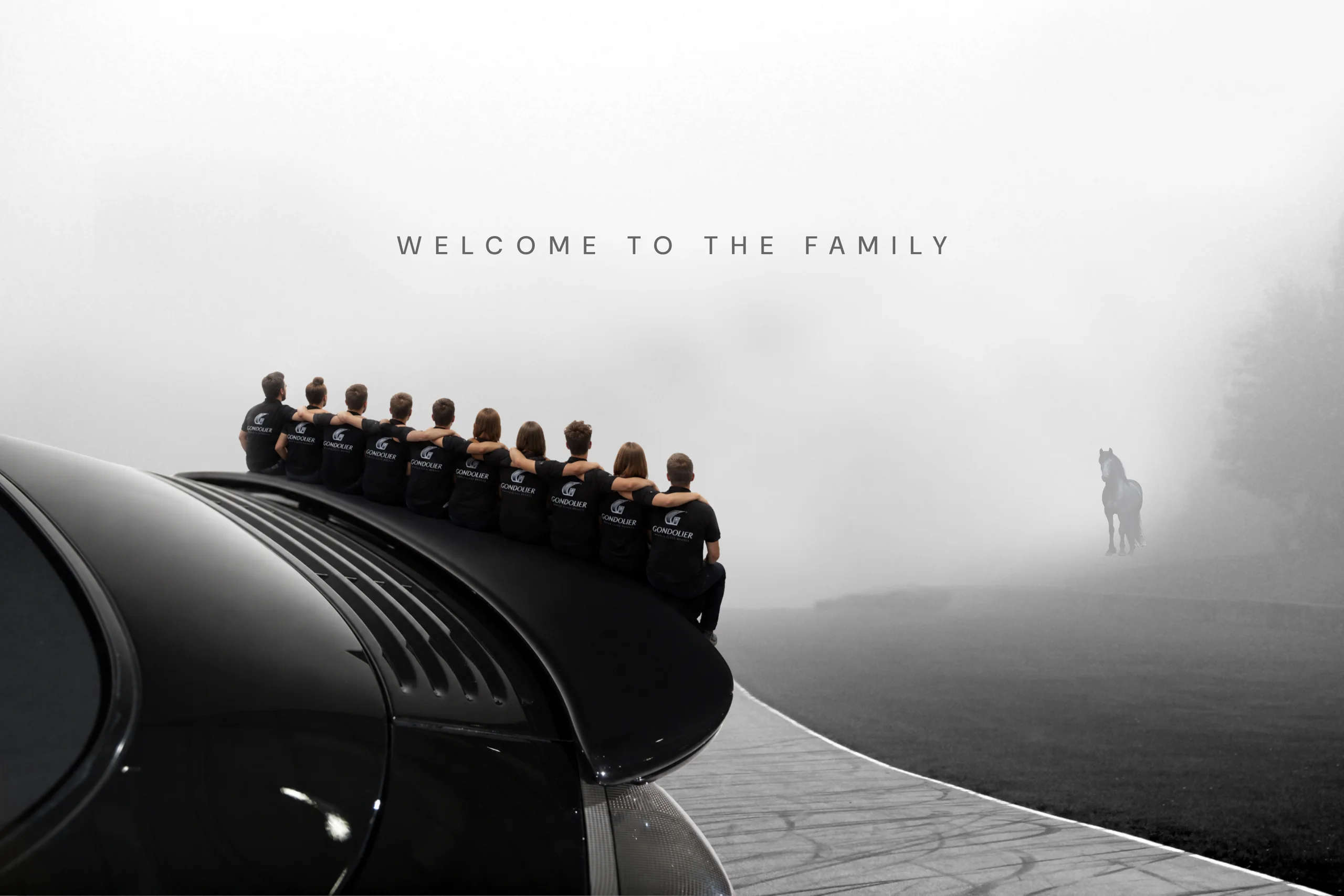 The Gondolier team sitting together on the wing of a black Porsche, a horse emerging from the fog ahead. Welcome to the family.